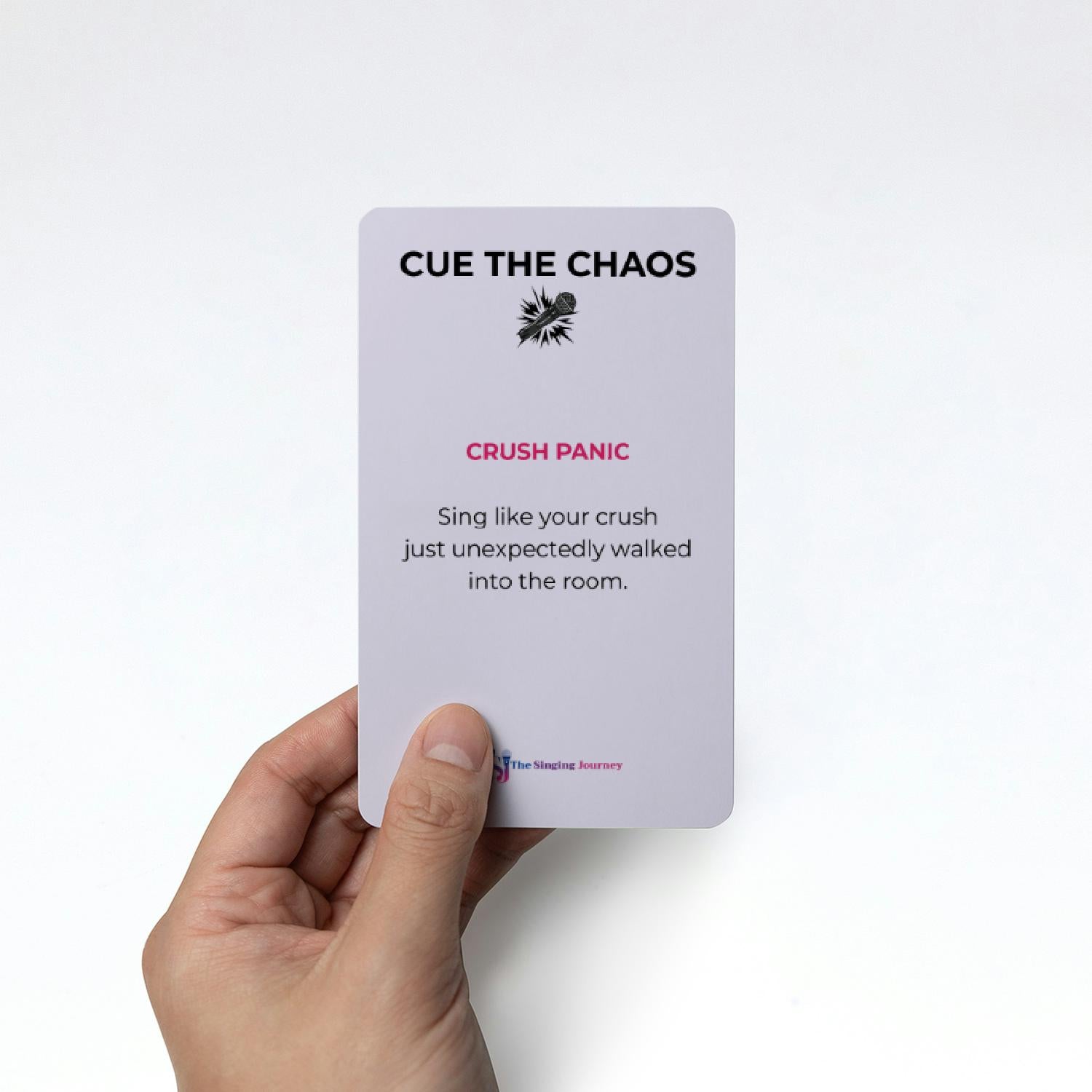 Hand holding a card with text 'CUE THE CHAOS' and 'CRUSH PANIC' on a white background